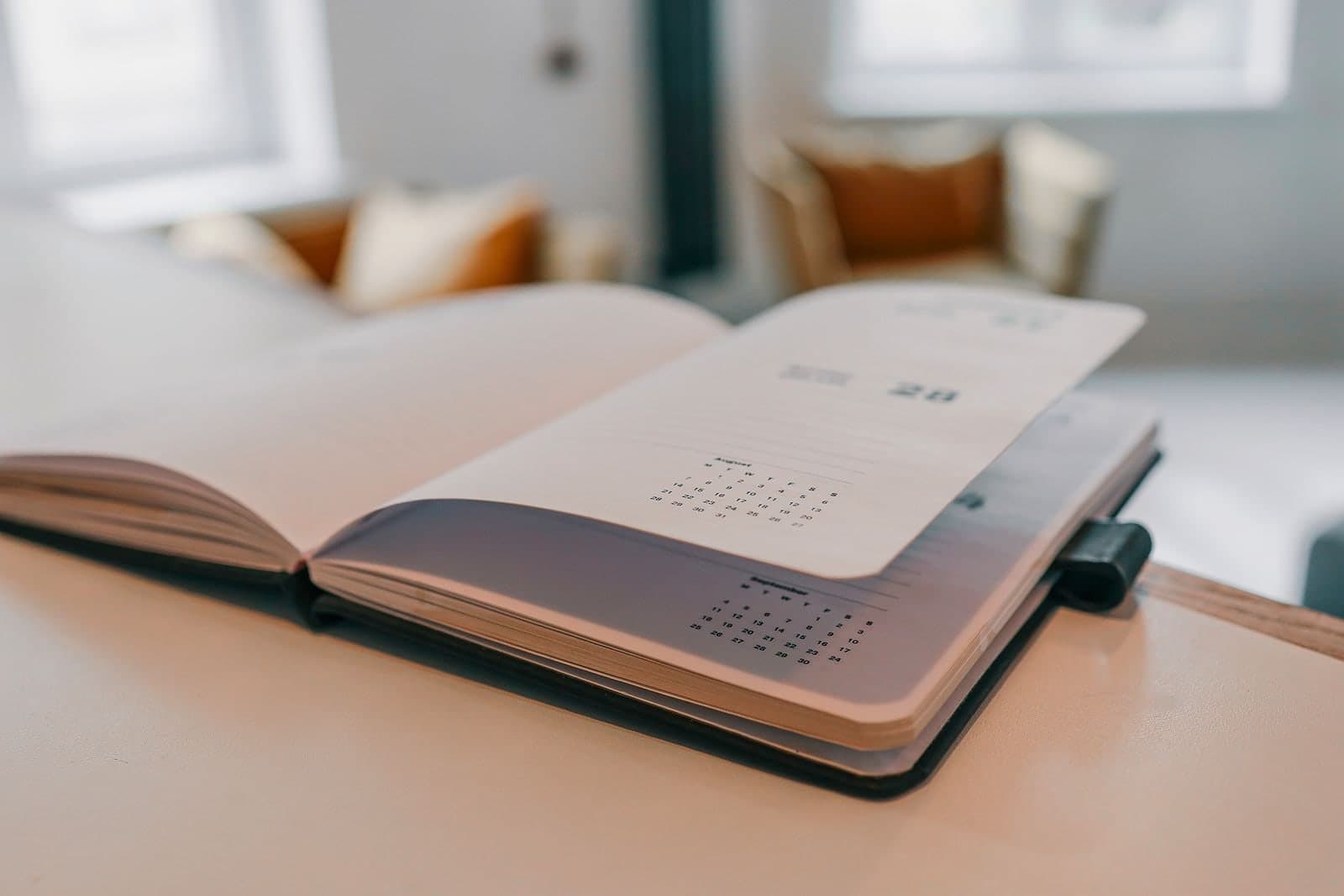 A paper planner lying open at a fresh month on a kitchen table.