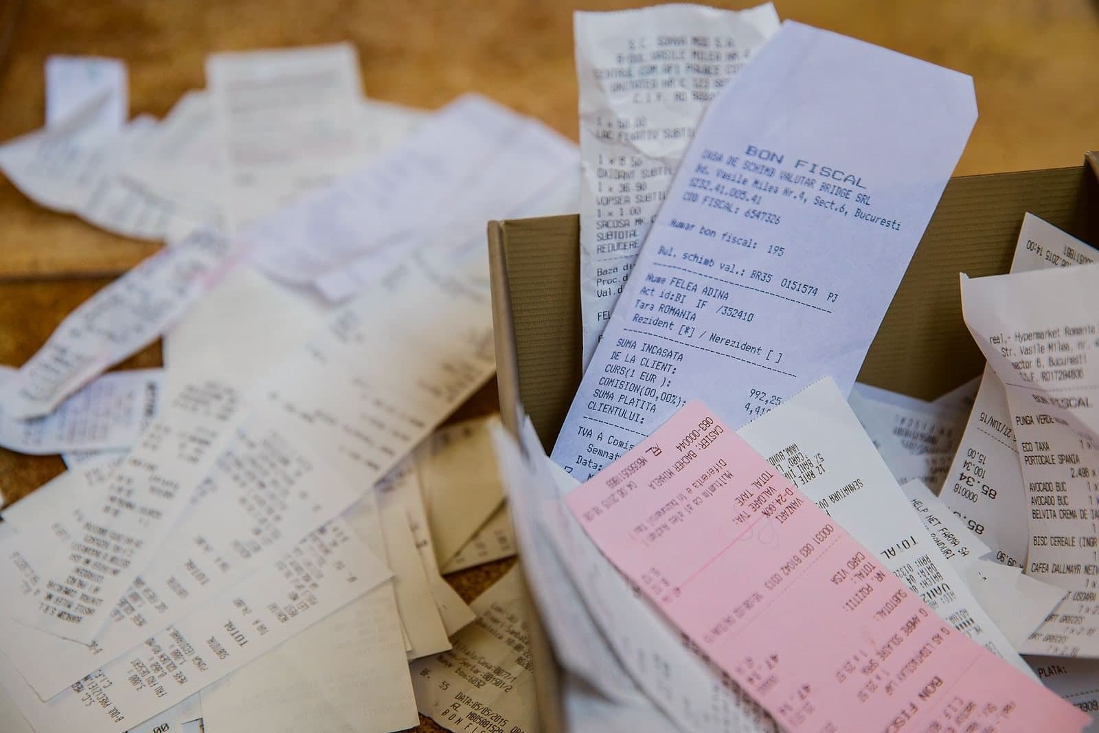 A box of receipts tipped over across a table, months of them loose.